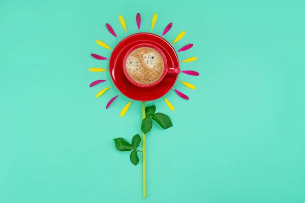 Cup of coffee with flower petals on a turquoise background.