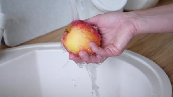 Musluğun altında beyaz bir kadının elinde kırmızı elma — Stok video