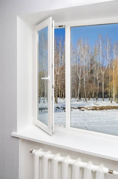 White window in empty room with heating and gray walls. Beautiful view from the window of the home.