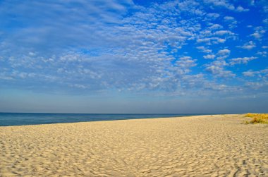 Mavi deniz karşı temiz, kumlu plaj.