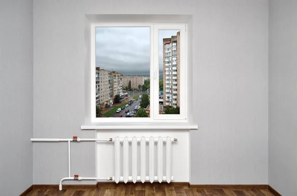 空房间里有白色的窗户 有暖气和灰色的墙壁 从家里的窗户看城市 — 图库照片