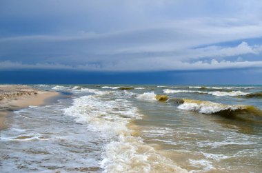 Dalgalar deniz temiz kumlu plaja yıkayın. Vahşi bir kumsalda manzara. Deniz fırtınası.