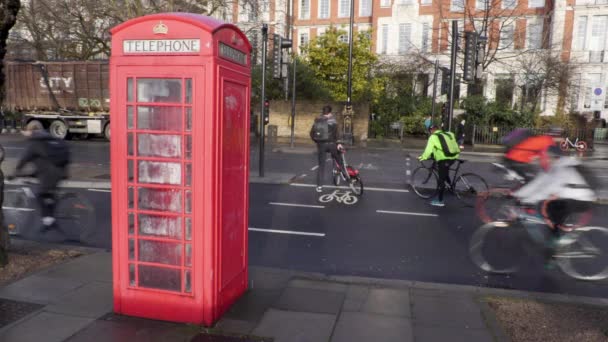 Kerékpárosok ciklus sávban megy múlt a brit telefon doboz az esőben — Stock videók