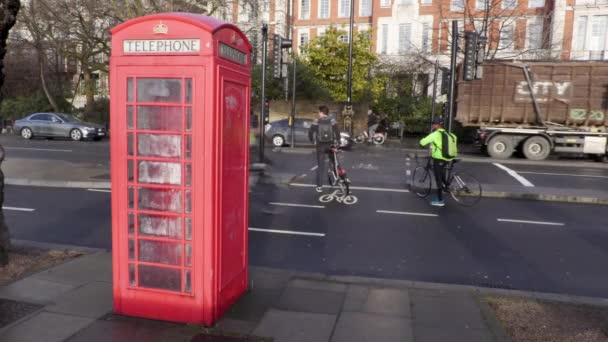 Kerékpárosok ciklus sávban megy múlt a brit telefon doboz az esőben — Stock videók