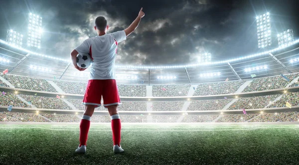 Futbol oyuncusu profesyonel stadyumda bir futbol topu tutuyor