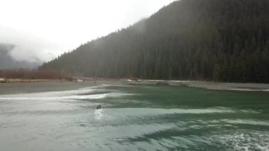 Bir yağmurlu kış gününde Alaska'da küçük dalgalar sörf çalışıyor