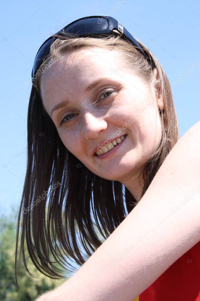 Girl with sunglasses on sky background smiling