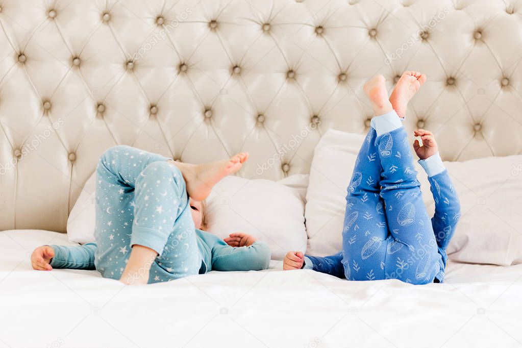 Legs raised up of a little children on white bed