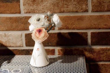 Beyaz seramik vazo masada yapay güller çiçekler. Klasik