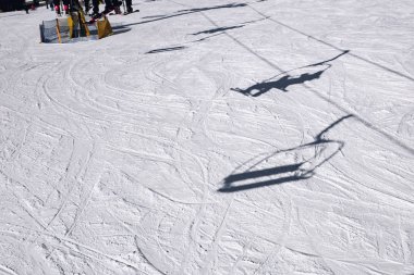 Dağ yamacında kayakçıların gölgeleri ski-li'ye çıkıyor.