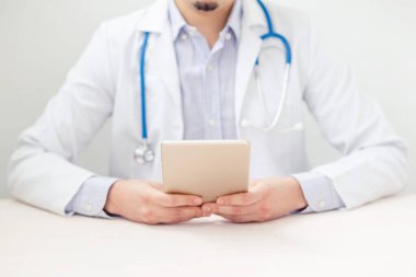 Konsültasyonda dijital tabletini kullanan erkek doktorun portresi. Teknoloji ve tıbbi konsept.