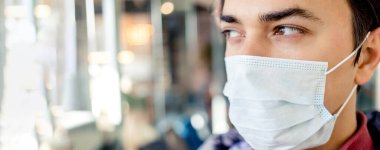Cerrahi maske takan adam. Coronavirus 2019-ncov salgını. Virüs ya da hastalık salgını sırasında etkileyici gözleri olan bir adamın portresi. Pankart.