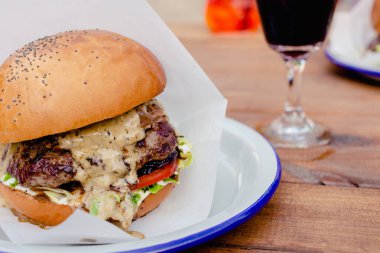 Mantarlı, domatesli, mikro yeşillikli, soğanlı, ahşap zemin üzerinde peynirli sosisli leziz gurme biftek. Sokak yemeği. Kapat..