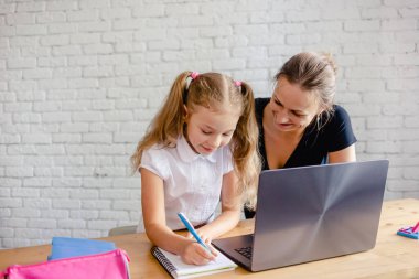 Annesiyle mutlu bir kız evde online çalışıyor. Corona virüsü ve karantina konsepti. Çevrimiçi öğrenme veya eğitim teknolojisi kavramı