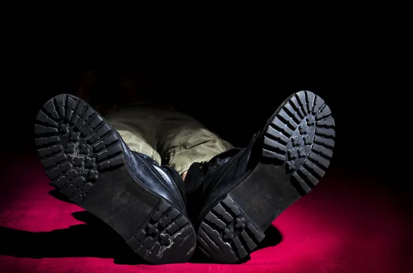 Men\'s legs in old military boots, lying on the floor.