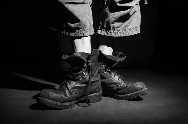 Men\'s legs in old military boots, standing, in black and white.