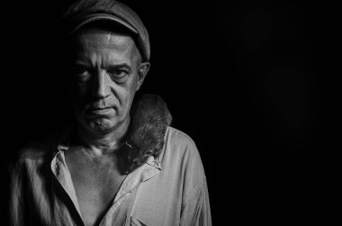 Karanlık onun omzuna yerli bir fare ile bir şapkalı yaşlı bir adam.