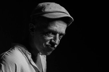 Karanlık bir arka plan üzerinde şapkalı yaşlı bir adam portresi .