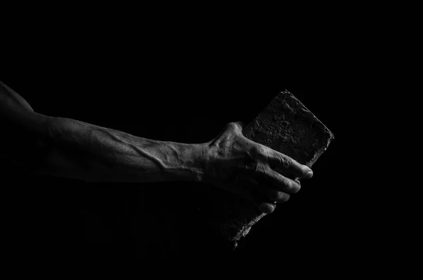 Man\'s hand holding a brick, in black and white.