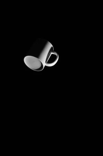 White cup floating in space on a black background.