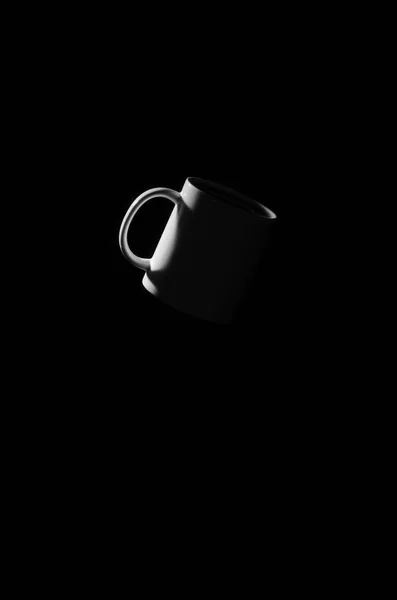 White cup floating in space on a black background.