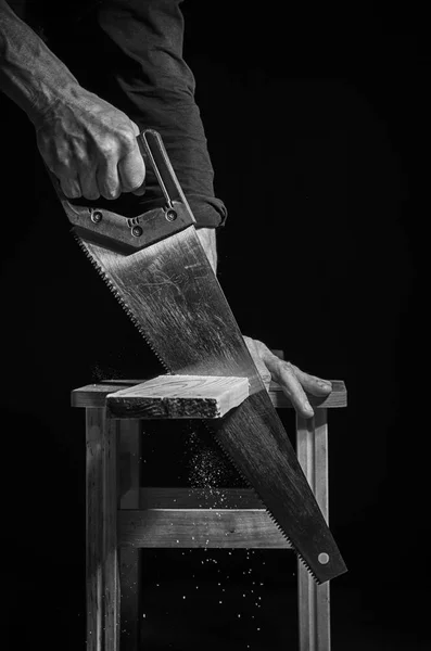 Adam bir tahta bir el testeresi ile kesme tezgahlar. — Stok fotoğraf