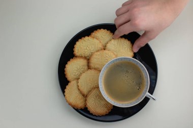 Ev yapımı shortbreads siyah plaka ve fincan sade kahve desenli. Çocuklar el holding bir kurabiye. Üstten Görünüm.