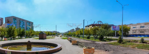 Panoramik manzaralı evler, üçlü, fenerler ve mağazaları tarafından kapsanan ana caddesi (sokak). Ön plan çeşme, saksı ve diğer banka içinde. Temirtau şehir. Karaganda bölge. Kazakistan.