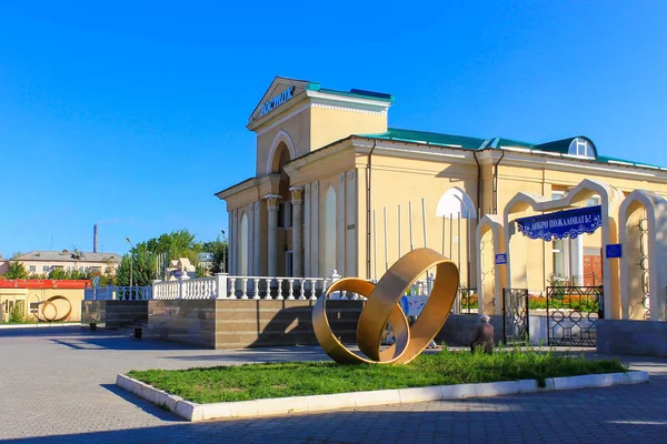 Entrée principale historique du grand théâtre de cinéma, appelé Wostok avec des monuments. L'entrée et l'arche du parc Kio sur la droite. Situé au centre-ville de Temirtau, région de Karaganda. Kazakhstan . — Photo