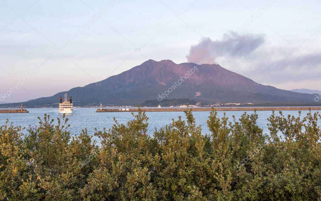 Eruption of the Vulcan Sakurajima and Kagoshima Ferry arriving the Port during summer sunset. Located in Kagoshima, Kyushu, South of Japan.