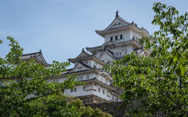 Yeşil bitki örtüsü ile kaplı açık, güneşli bir gün Himeji Kalesi yakın görünümü. Himeji, Hyogo, Japonya, Asya.