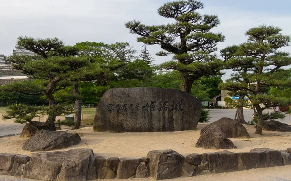 Himeji Castle Stone Monument, lettering in engl. UNESCO World Heritage, on a clear, sunny day with many green around. Himeji, Hyogo, Japan, Asia. — Stock Photo, Image