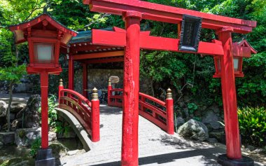 Geleneksel kırmızı Köprü, Fener ve Torii Japon Jigoku Meguri Shinto Tapınağı yeşil bir manzara ile çerçeveli. In Beppu, Oita Prefecture, Japonya, Asya.