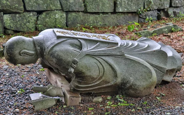 Dropped down, fallen buddhist monk granite stone statuesque in a Temple in Japan. Higo Honmyo Temple, Kumamoto Prefecture, Japan, Asia. — Stock Photo, Image