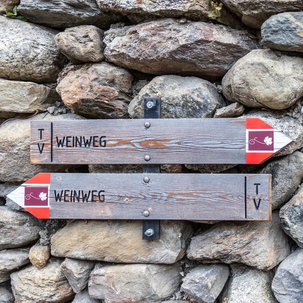 Wine Road'a turistleri yönlendiren iki tabela, Almanca, Weinweg, arka planda taş duvar. Ayrıntı görünümü.