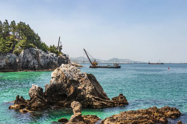 Jeungsan Beach with cliffs, industrial ships and mountains in background. Donghae, Gangwon Province, South Korea, Asia.