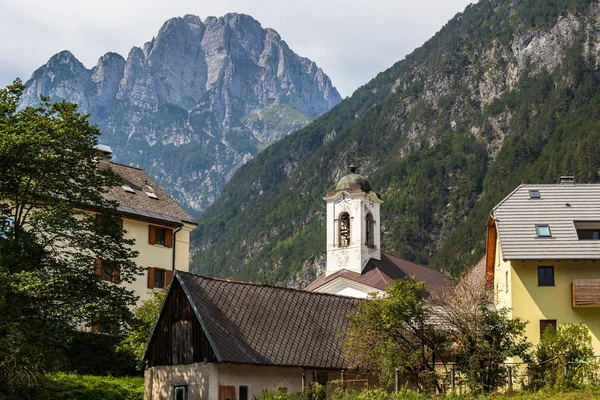 Vista sobre la Iglesia Parroquial Central y los Edificios de Log pod Mangartom con el Monte Rombon en el fondo. Bovec, Eslovenia, Europa . — Foto de Stock