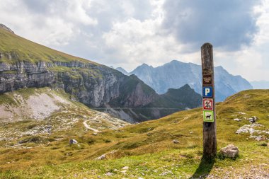 Mangart Saddle, Mangartsko sedlo üstüne ipuçları ile Triglav Milli Parkı İşareti. Mangart Yolu, Mangartska cesta, arka planda. Bovec, Slovenya