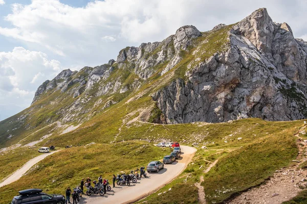 Panoramic view on Mount Buconig and Mangart Road, Mangartska cesta, with parking Cars, Motor Bikes and People. Taken from Mangart Saddle. Slovenia. — Stock Photo, Image