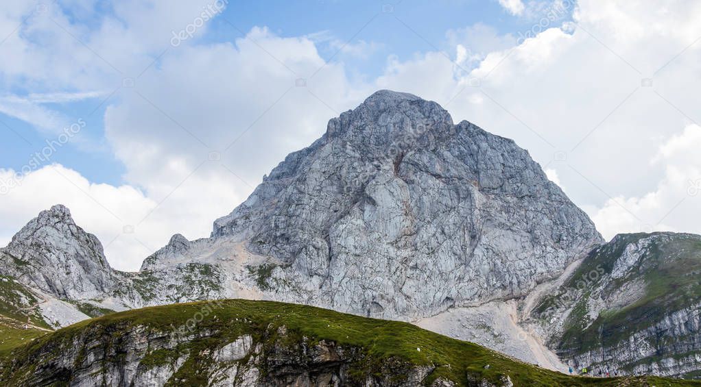 Panorama of western wall of Mount Mangart with Hikers in the Julian Alps. Shoot from Mangart Saddle, Mangartsko sedlo. Border of Slovenia and Italy