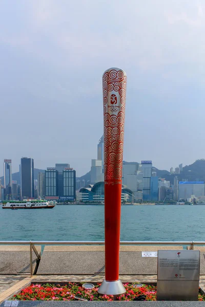 Olimpiyat Oyunları Anıtı. Gezinti güvertesinin yakınındaki Yıldızlar Bulvarı 'nda. Arka planda Hong Kong 'un silüeti var. Tsim Sha Tsui, Hong Kong, Çin.