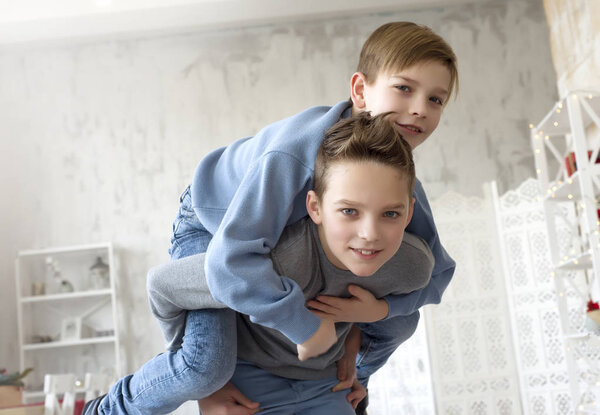 Милые счастливые братья веселятся дома. Лучшие друзья развлекаются в помещении. Портрет двух мальчиков. Братья играют дома. Веселое настроение в светлый день. Дети обнимаются и улыбаются.
.