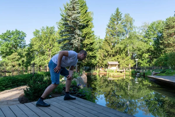 Een jonge man staat op een houten dek en kijkt naar iets in het water. Dawn Rechtenvrije Stockfoto's