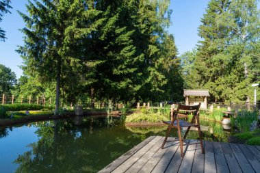 Şafak vakti. Katlanır ahşap sandalye küçük bir güzel gölet önünde ahşap bir zemin üzerinde duruyor