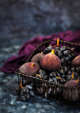 Taze incir ve koyu ahşap arka plan üzerinde sepette mor üzüm