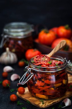 Kurutulmuş domates sarımsak ve koyu arka plan üzerinde bir kavanoza zeytin yağı ile