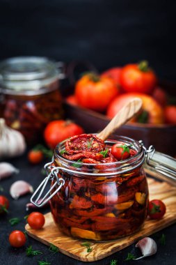 Kurutulmuş domates sarımsak ve koyu arka plan üzerinde bir kavanoza zeytin yağı ile