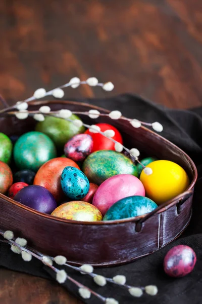 Easter colorful painted eggs and willow on dark rustic background, spring holiday concept