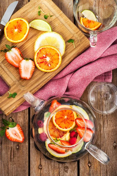 Chá vermelho de frutas com laranjas e bagas na mesa de madeira, vista superior — Fotografia de Stock