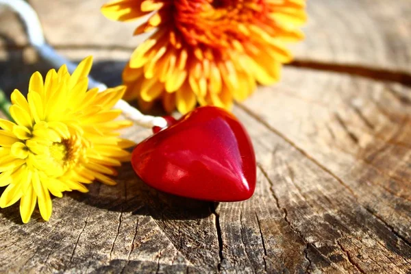 a red heart and flowers on wooden ground